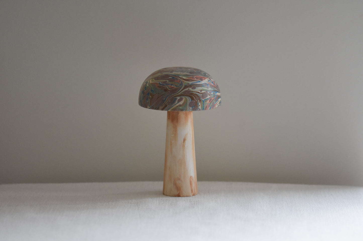 Jemma Lewis marbled wooden decorative toadstool on a beige background.