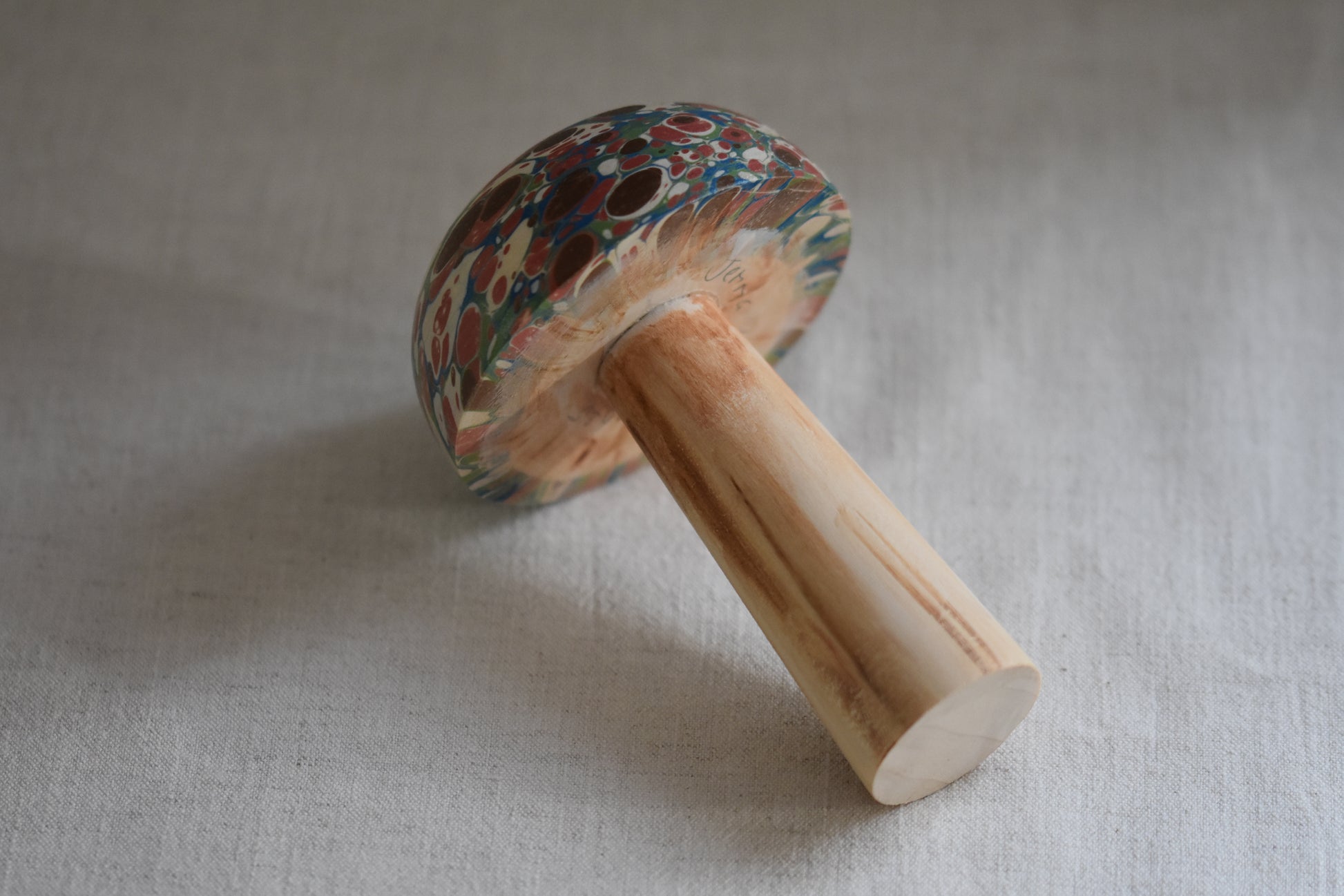 Jemma Lewis marbled wooden decorative toadstool lying down on a beige background.
