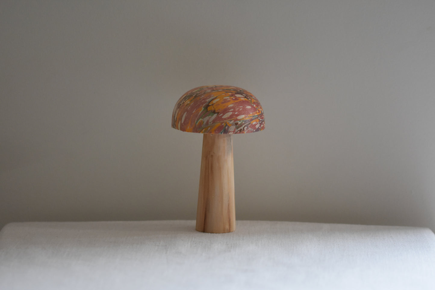 Jemma Lewis marbled wooden decorative toadstool on a beige background.