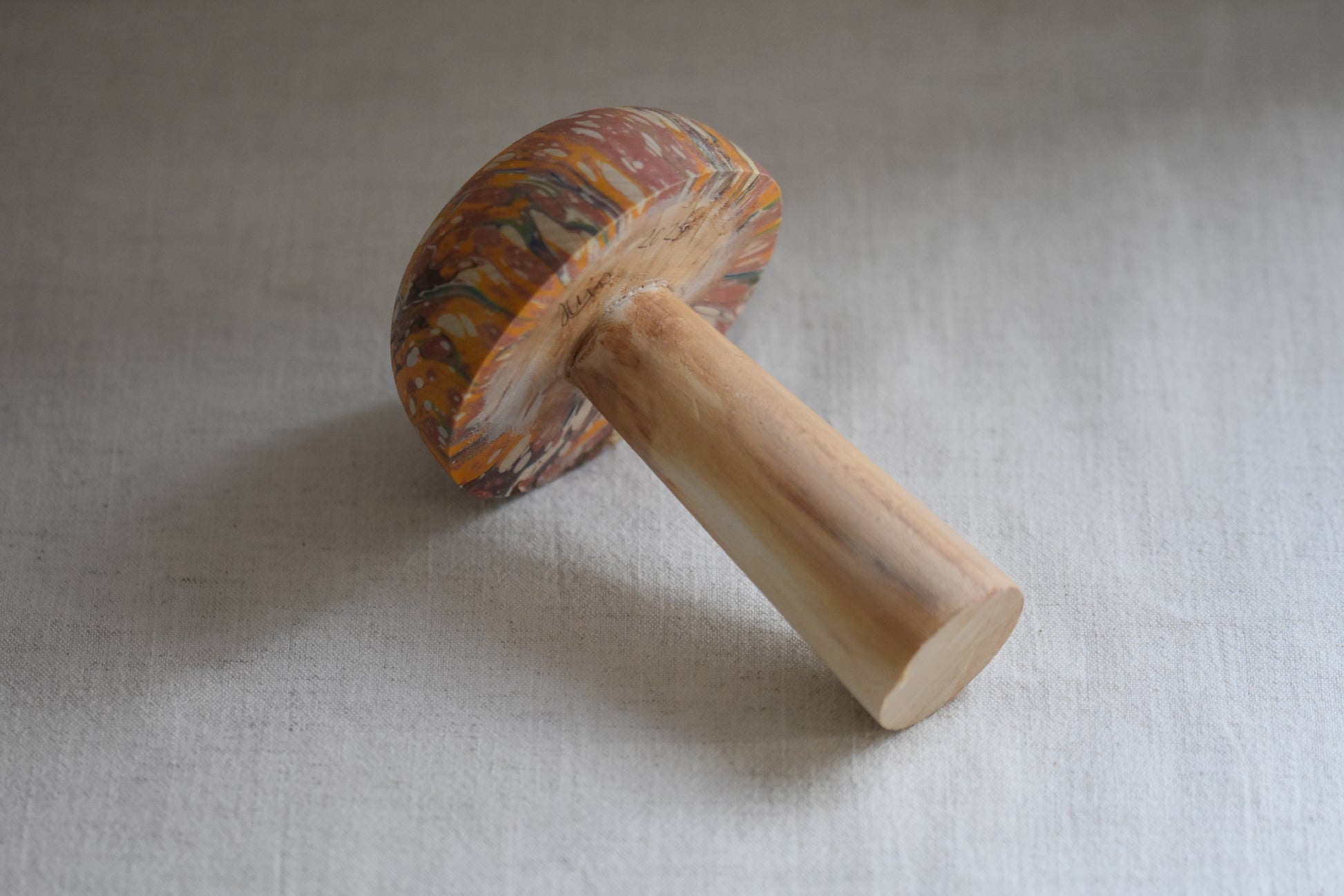 Jemma Lewis marbled wooden decorative toadstool lying down on a beige background.