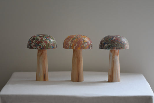 Jemma Lewis 3 marbled wooden decorative toadstool mushrooms figurines on a beige background.