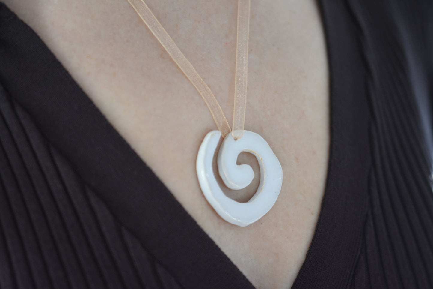 AEA Studio white mini stoneware ceramic swirl spiral pendant on a beige ribbon necklace.