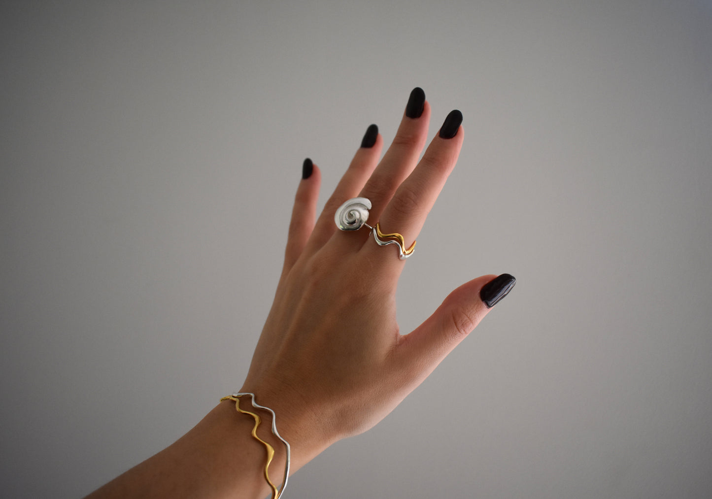 Hannah Bourn Saccostrea wavy rings and bangles in gold and silver with Periwinkle swirl spiral ring in silver.