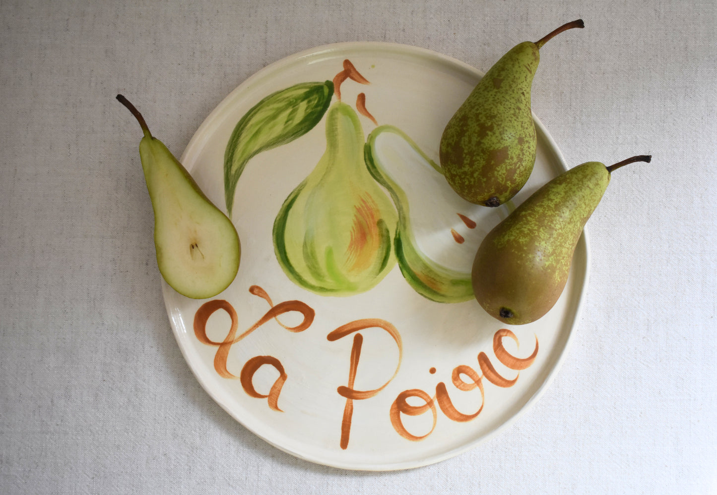 Harlie Brown earthenware ceramic La Poire plate with painted pear design and french writing.