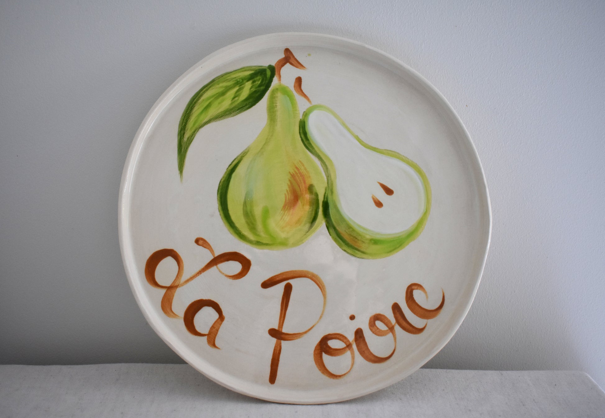 Harlie Brown earthenware ceramic La Poire plate with painted pear design and french writing.