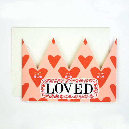 Hadley Paper Goods Loved party hat crown shaped card with heart design in red and pink.