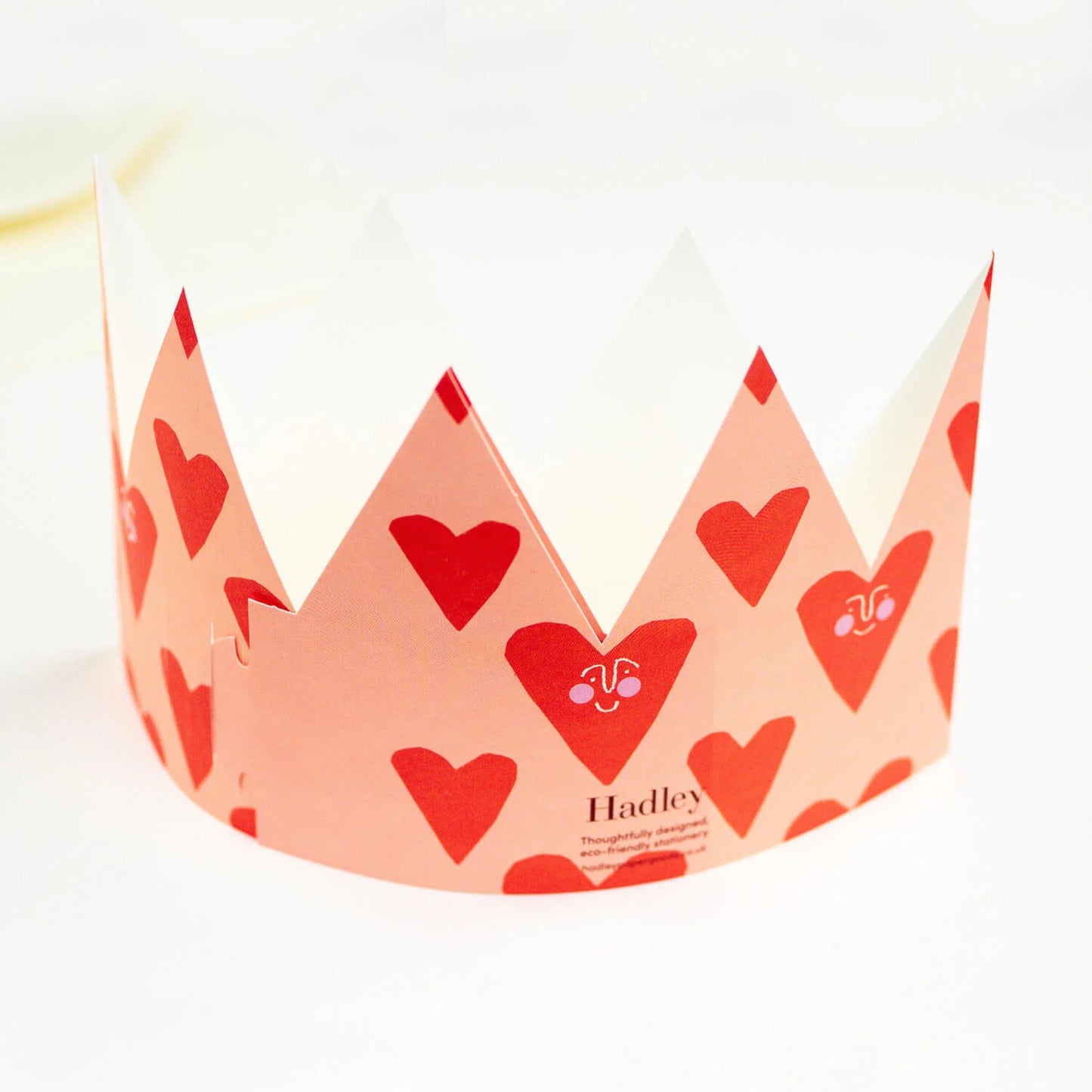 Hadley Paper Goods Loved party hat crown shaped card with heart design in red and pink, back view, on a white background.